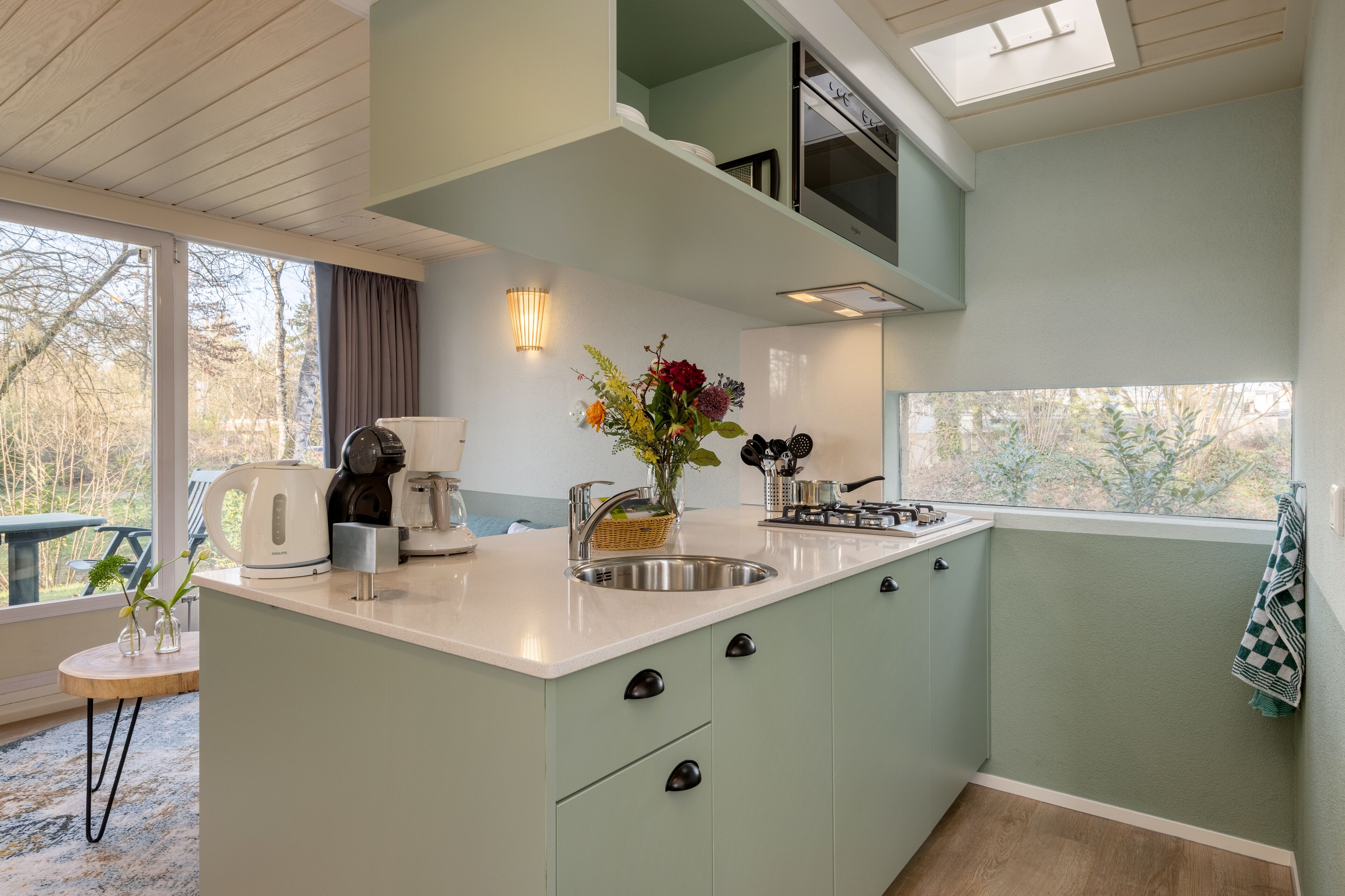 A compact kitchen with a central island, a built-in oven, and a window providing a view of the outdoors.