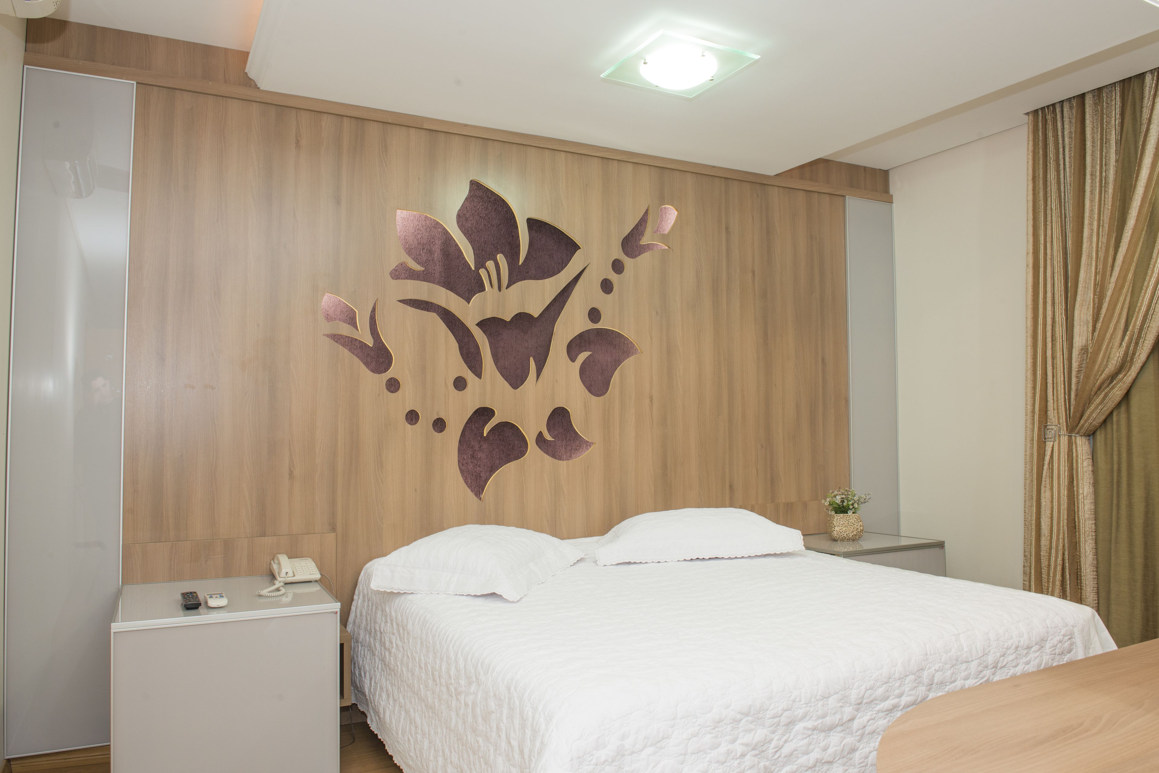 A neatly arranged hotel room with a bed, bedside table, and a decorative wall panel.