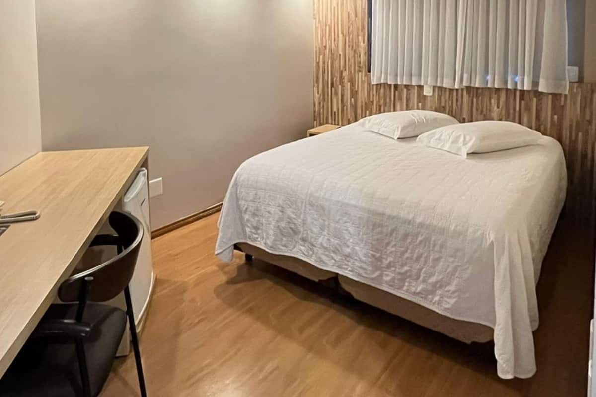 Una habitación de hotel compacta con una cama, un escritorio y una silla.