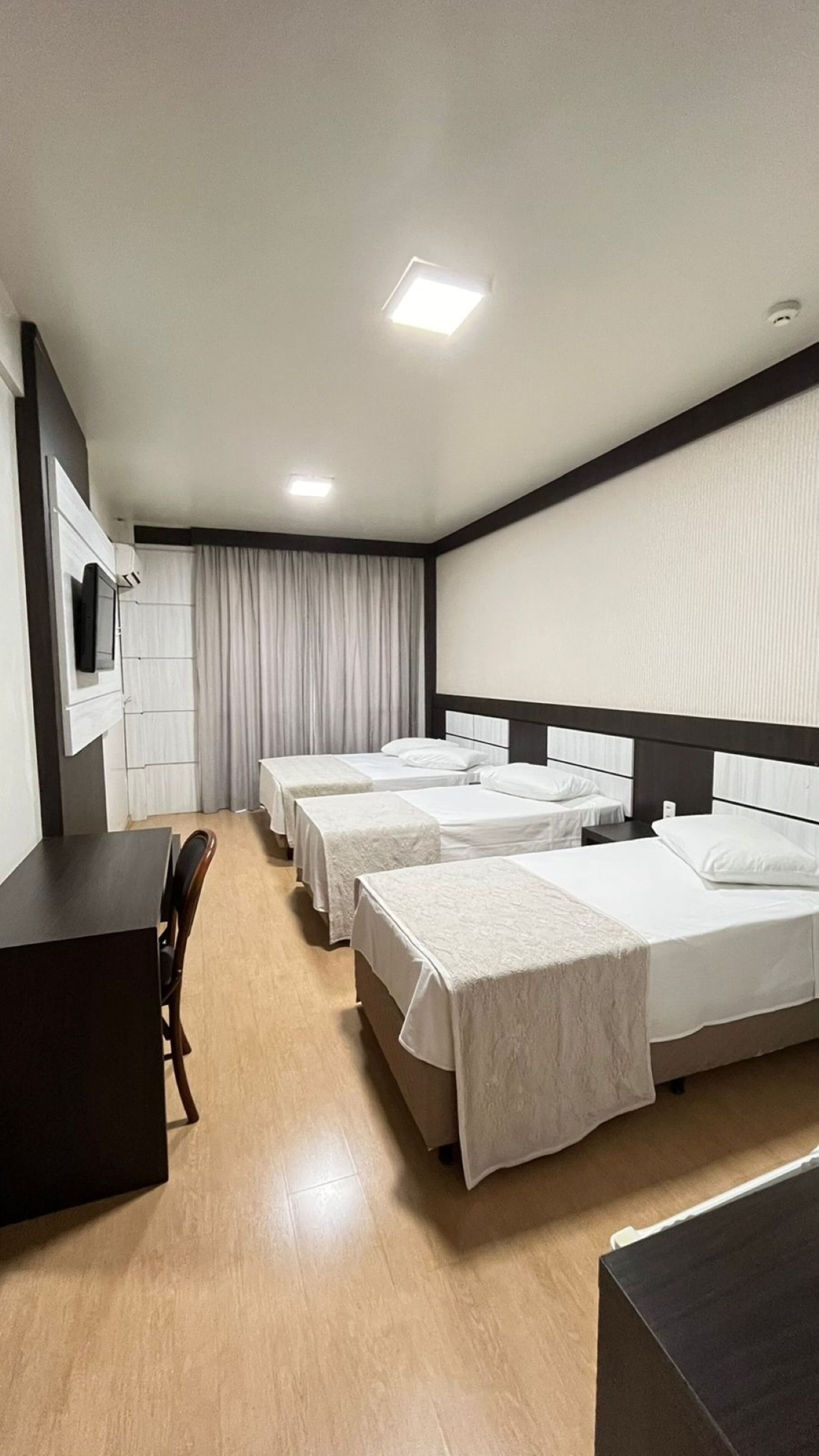 Una habitación de hotel con tres camas, un escritorio y un televisor.