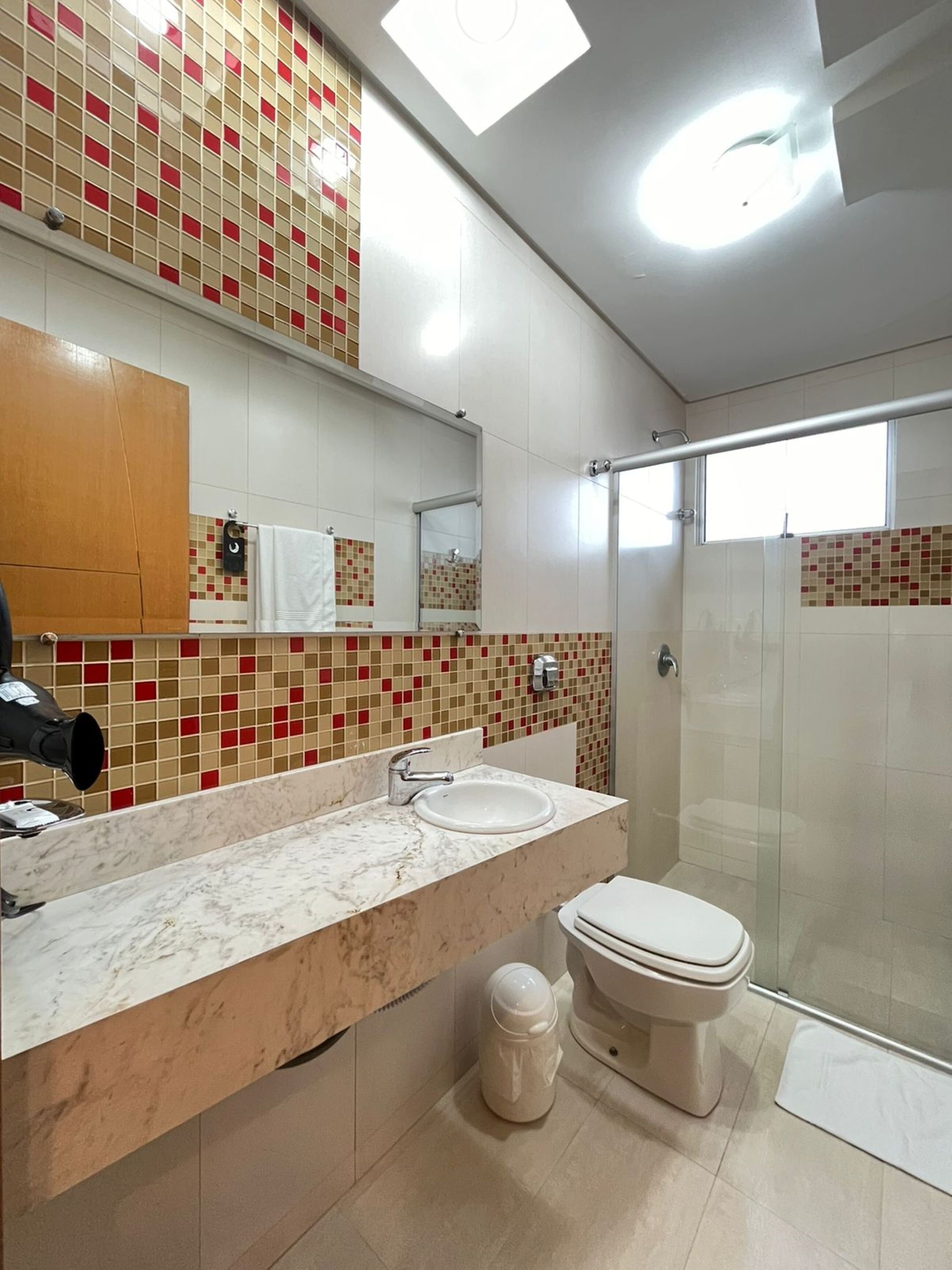 A modern bathroom with a marble sink, a toilet, and a glass shower enclosure.