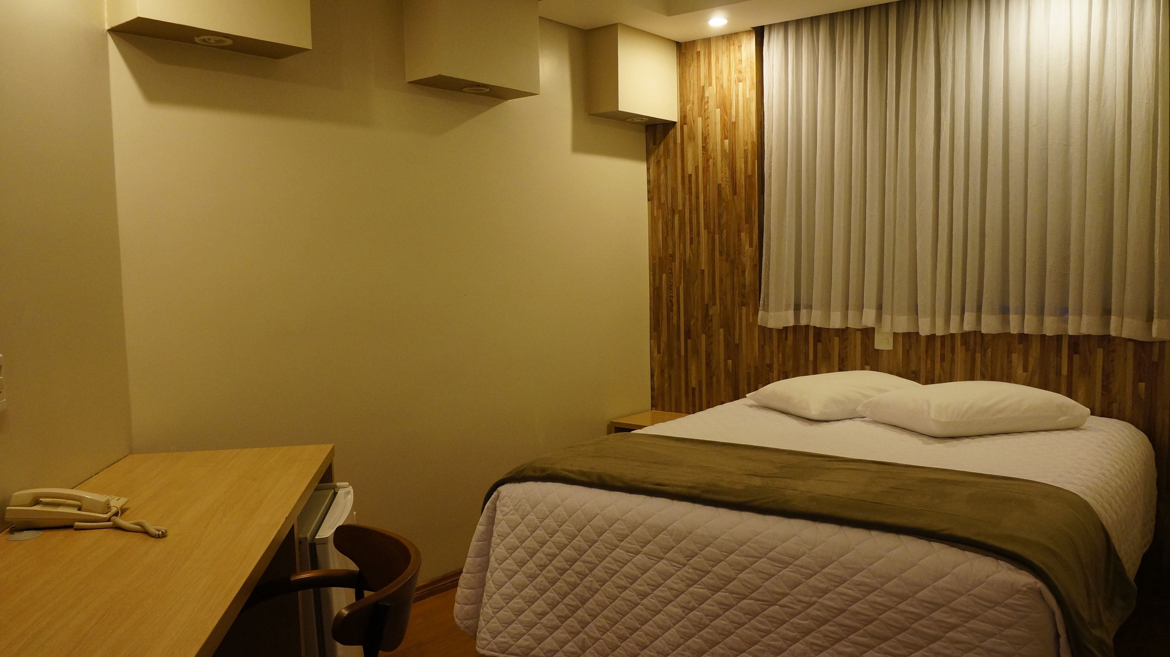 Una habitación de hotel con una cama, un escritorio y un teléfono.