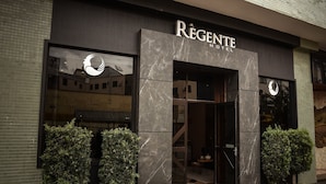 L’extérieur de l’hôtel Régente se distingue par sa façade moderne, ses grandes fenêtres et son logo bien visible.