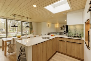 Una cocina moderna con una isla grande, armarios de madera y un tragaluz.