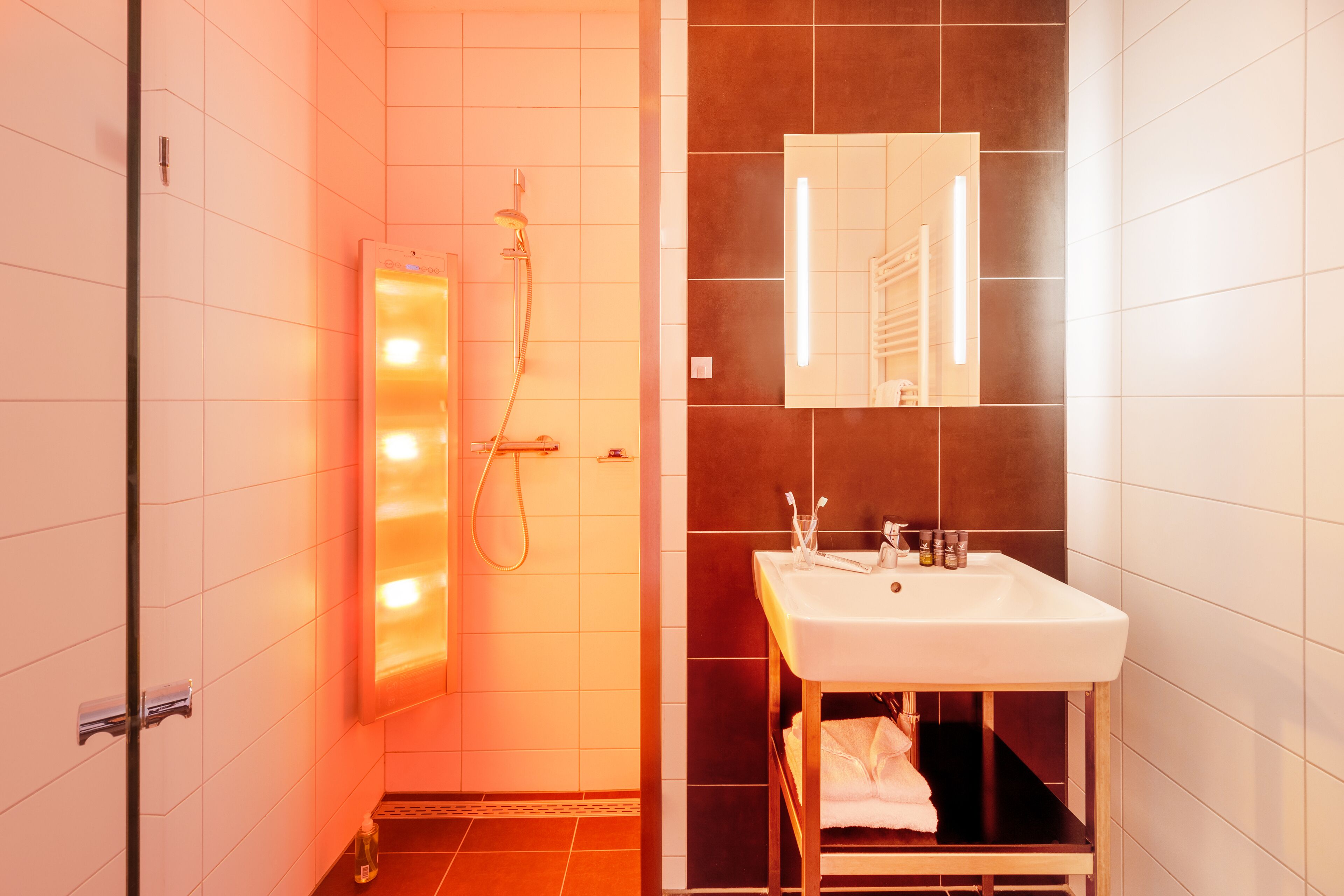 Ein modernes Badezimmer mit einem weißen Waschbecken, einem Spiegel und einer Dusche mit Duschbrause.