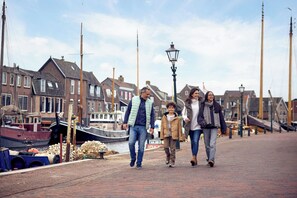 Un paseo marítimo con barcos amarrados a la izquierda, bordeado por casas tradicionales.