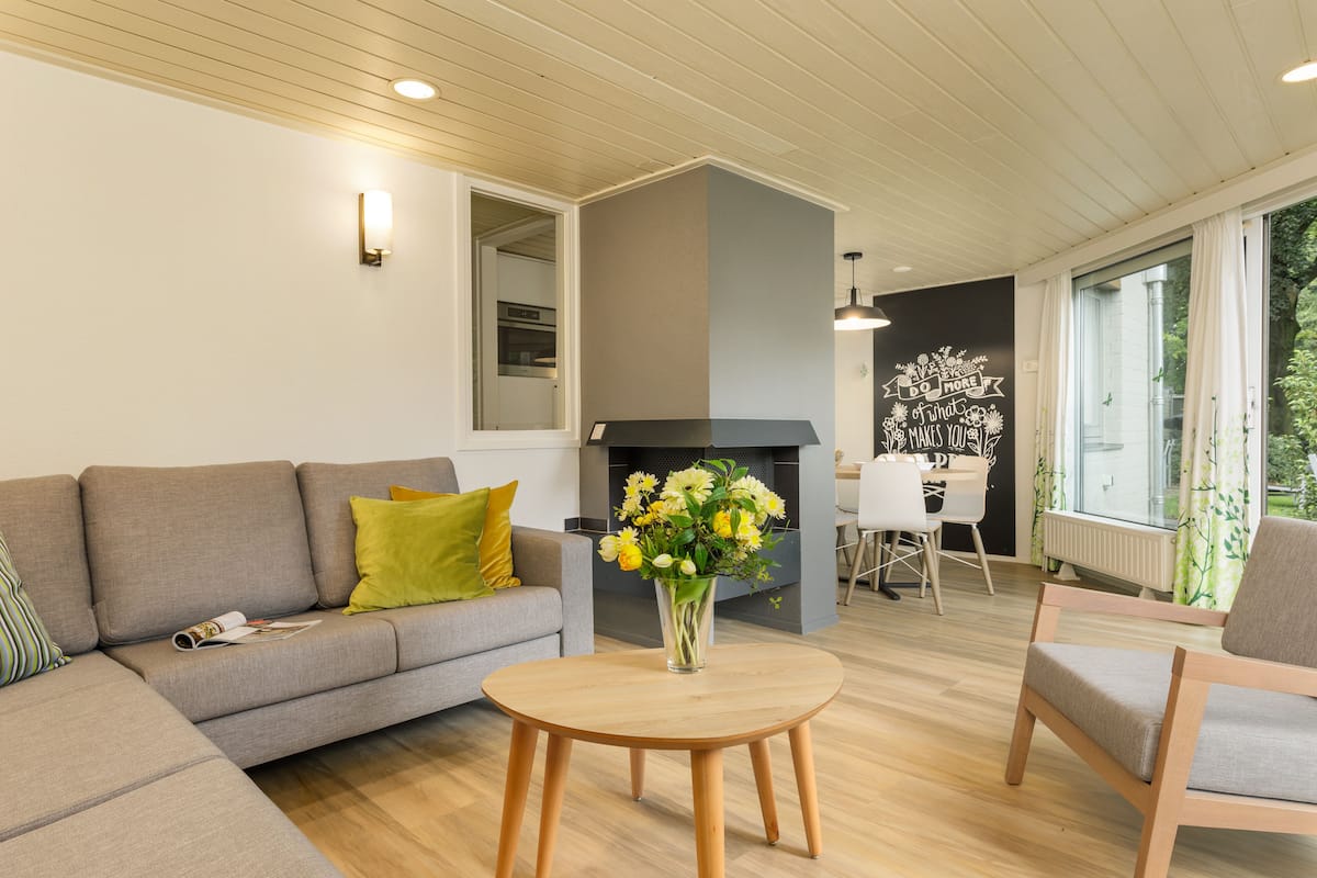 A modern living room with a grey sofa, a round wooden coffee table, and a fireplace.