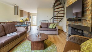 A modern living room with a sofa, a coffee table, and a fireplace. - Center Parcs Port Zélande (Ouddorp)