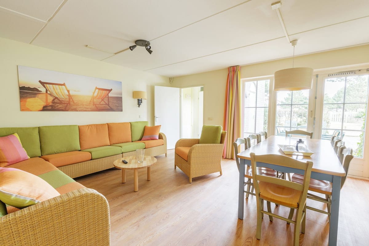 Una sala de estar con sofá, sillas, una mesa de comedor y un cuadro de sillas de playa.