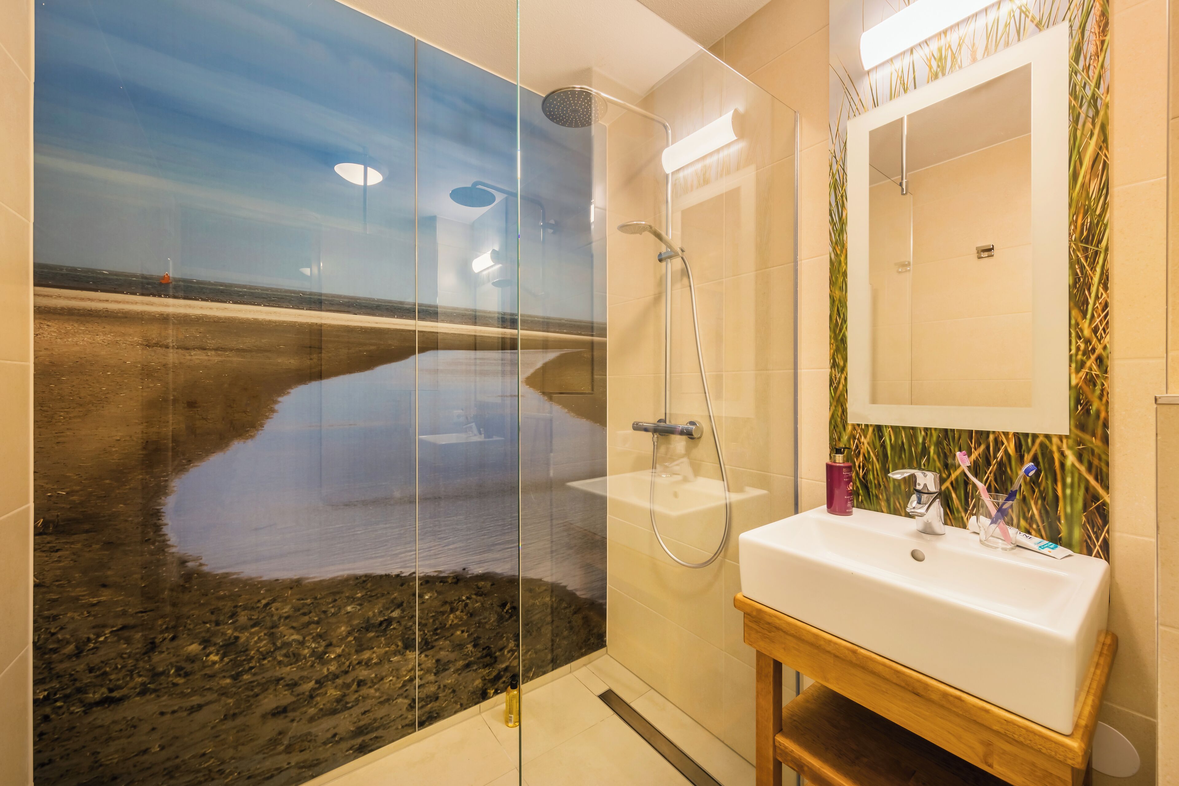 Een badkamer met een douchecabine van glas, een wastafel en een spiegel.