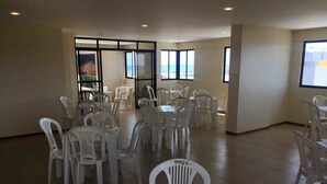 Un amplio espacio interior con varias mesas y sillas de plástico blanco dispuestas para un ambiente de comedor informal.