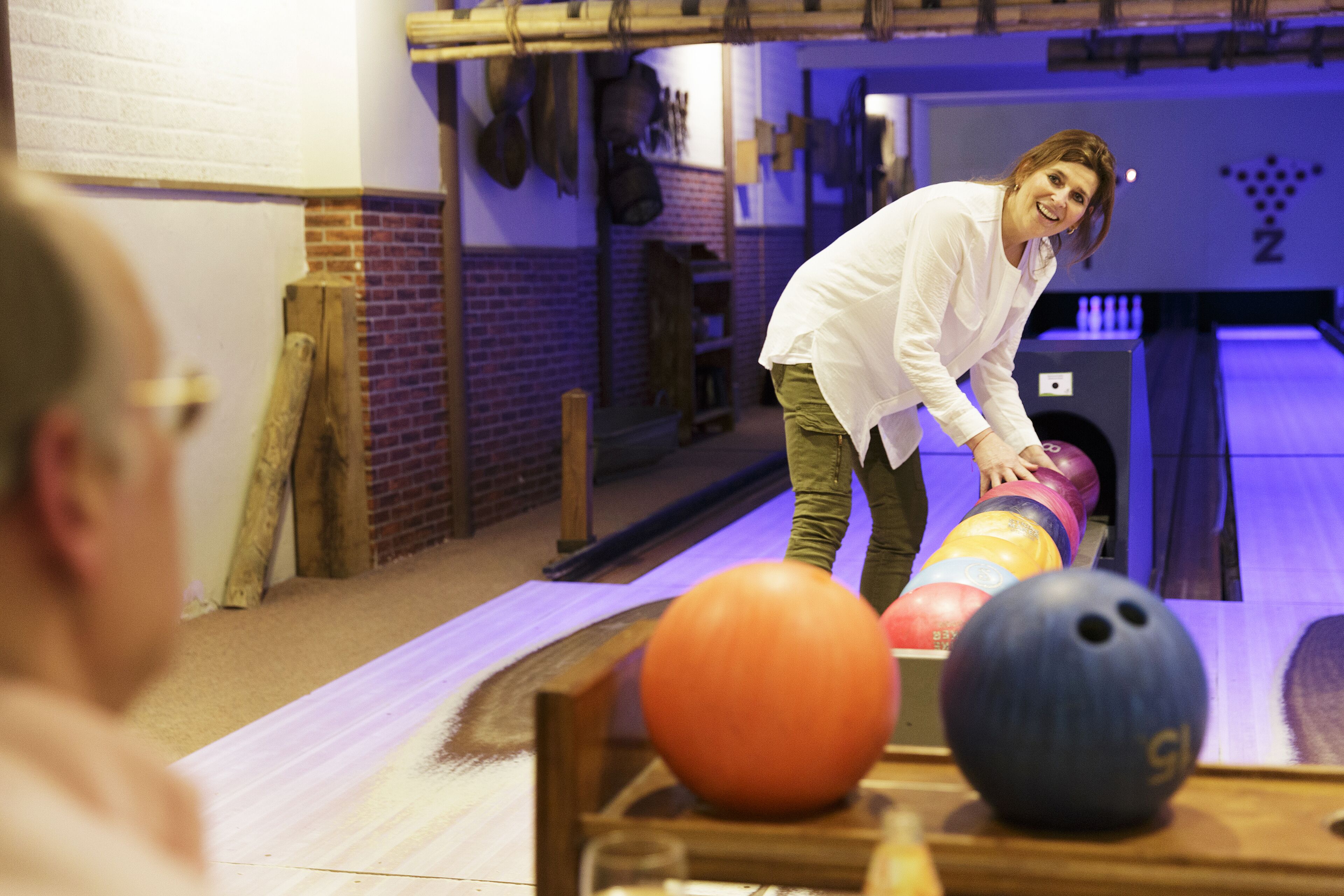 A bowling alley with wooden lanes, a bowling ball, and pins.