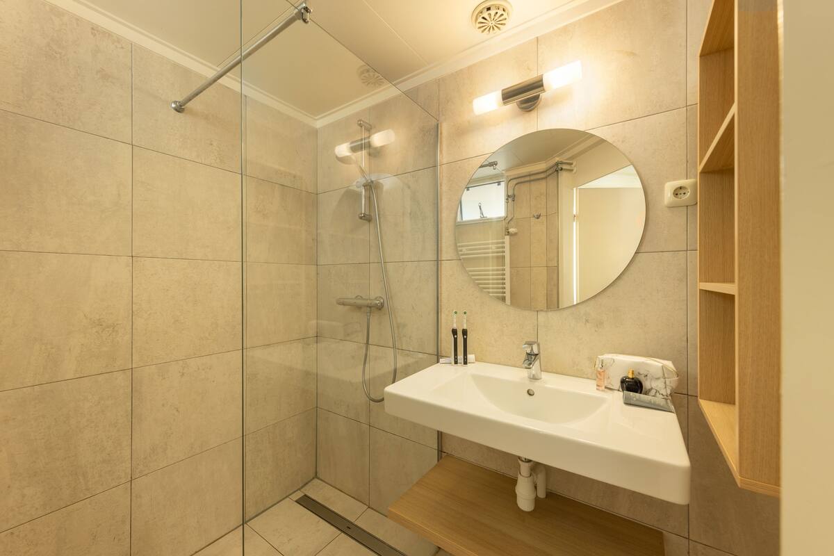 A modern bathroom with a glass-enclosed shower, a white sink, and a wooden vanity.