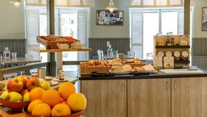 Buffet de café da manhã com frutas, pão e doces.