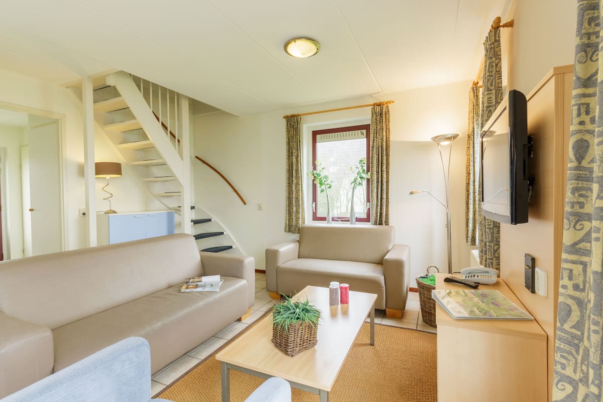 A living room with a sofa, a coffee table, a TV, and a staircase.