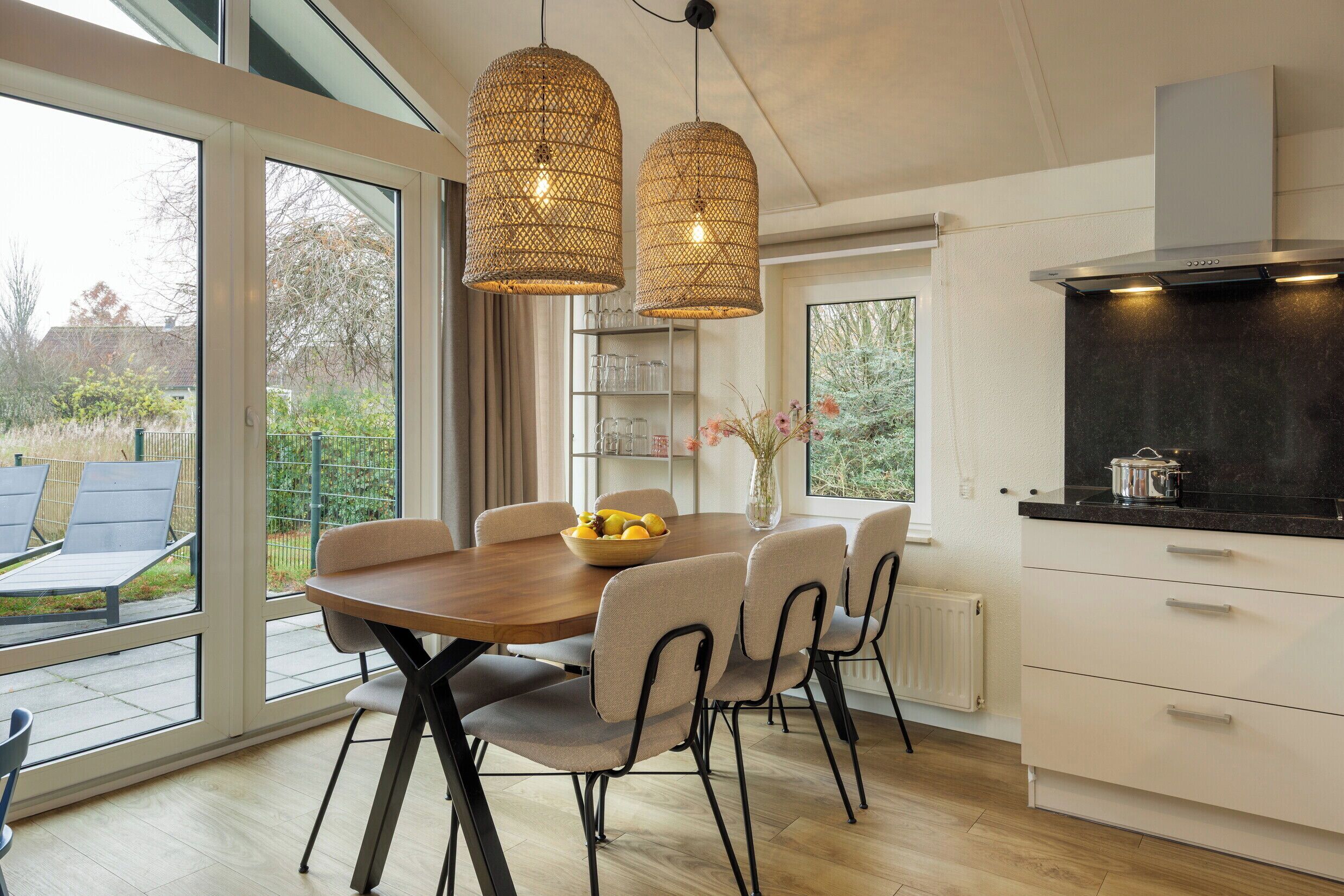 A modern kitchen with a dining area, large windows, and a view of the outdoors.