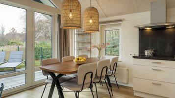 A modern kitchen with a dining area, large windows, and a view of the outdoors.