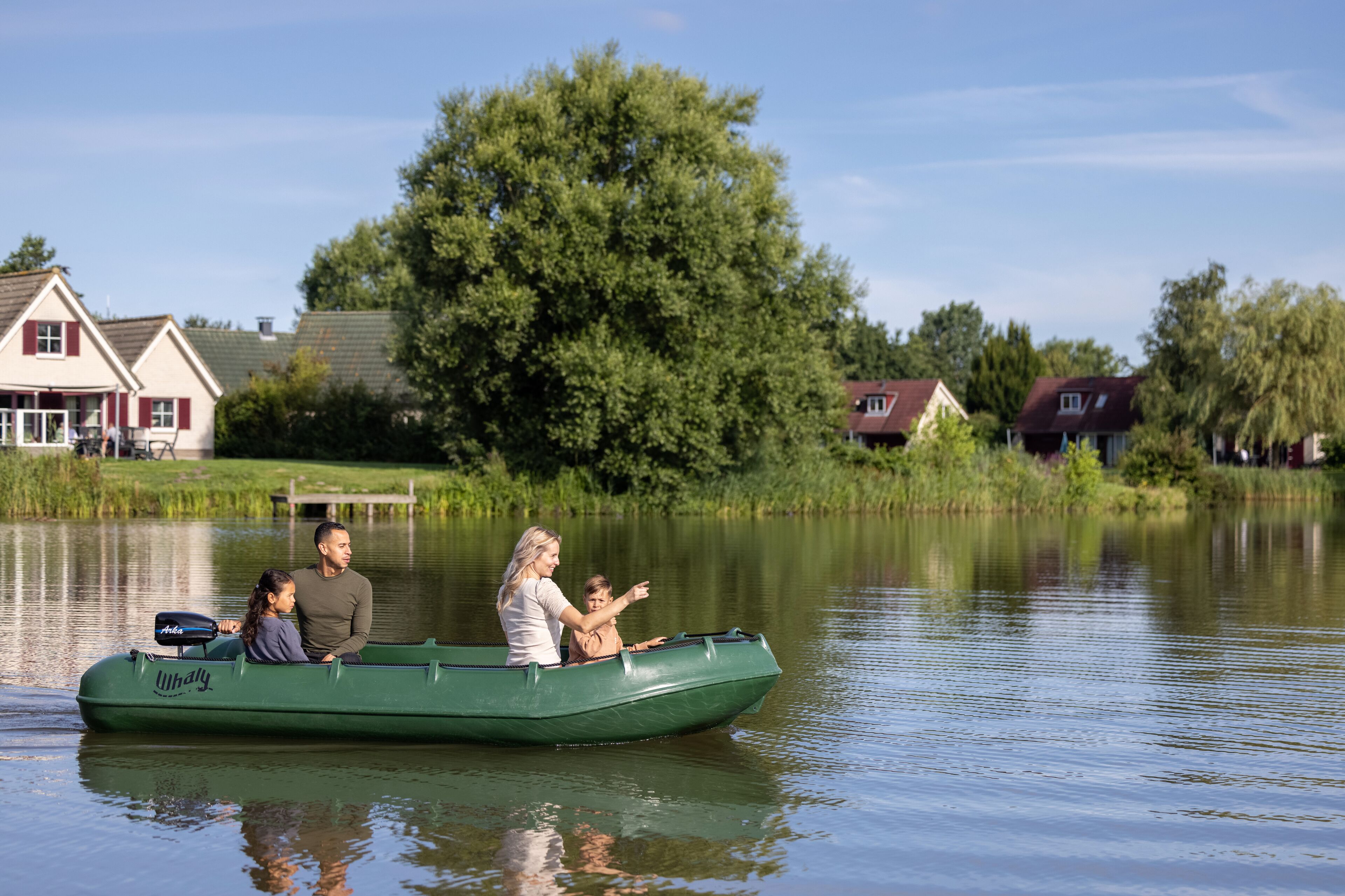 Een groene boot op kalm water, met een gezin.