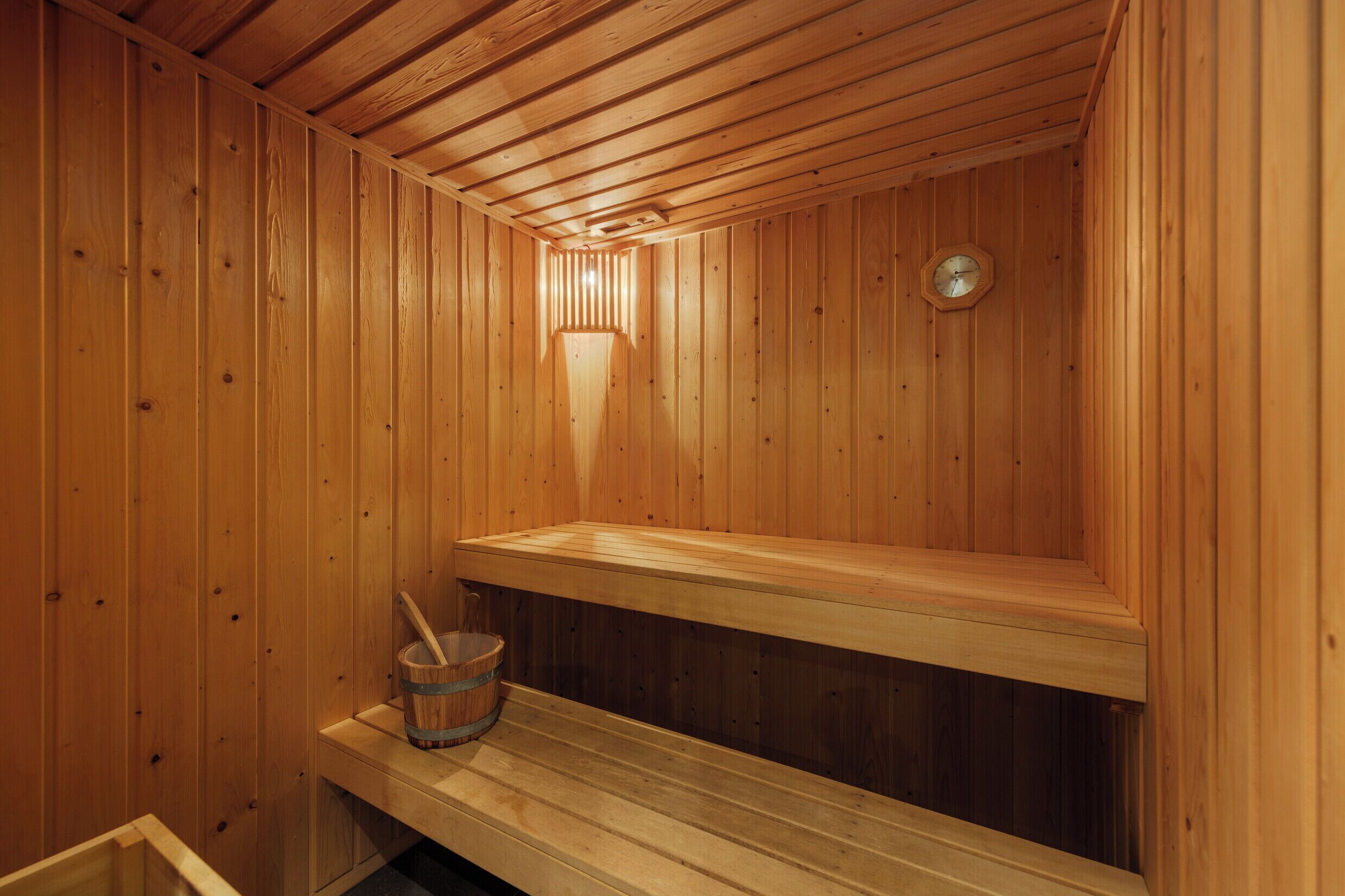A wooden sauna with benches and a bucket.