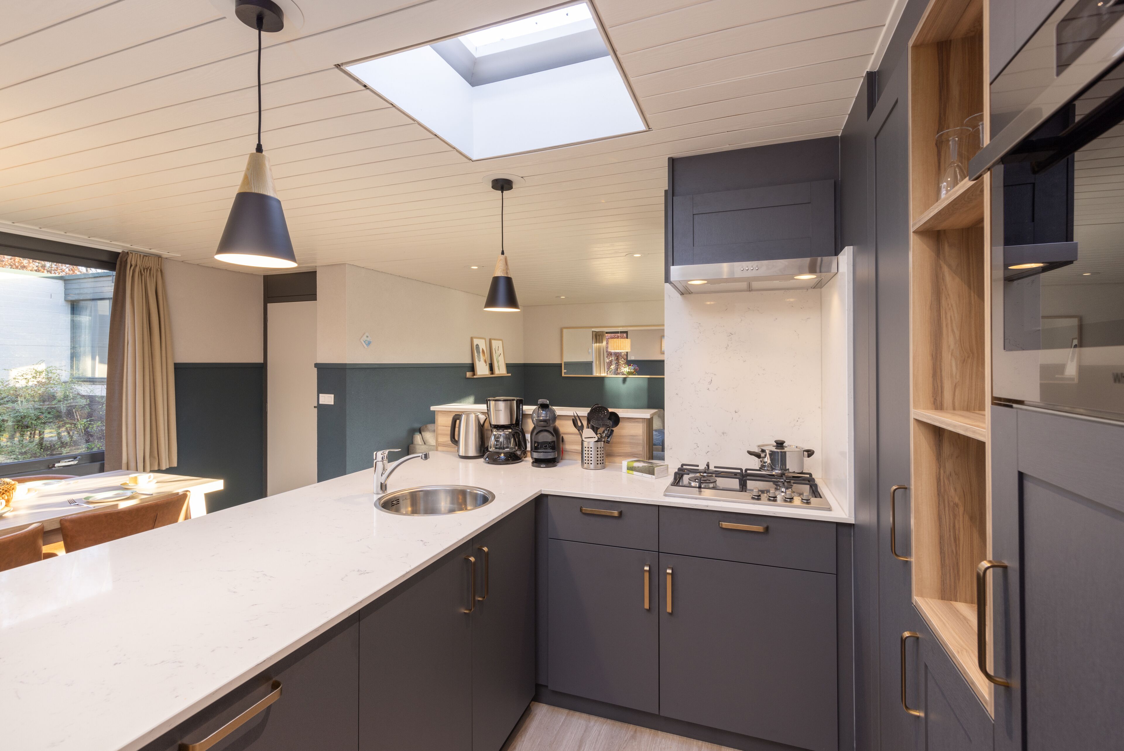 A modern kitchen with a skylight, dark cabinets, and a white countertop.