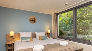 A neatly made bed with a striped bedspread, two bedside lamps, and a wall clock. - Center Parcs De Vossemeren (Lommel)