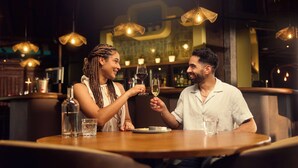 A couple at a restaurant table with a bottle of water, a glass of wine, and a plate of food. - Center Parcs De Vossemeren (Lommel)