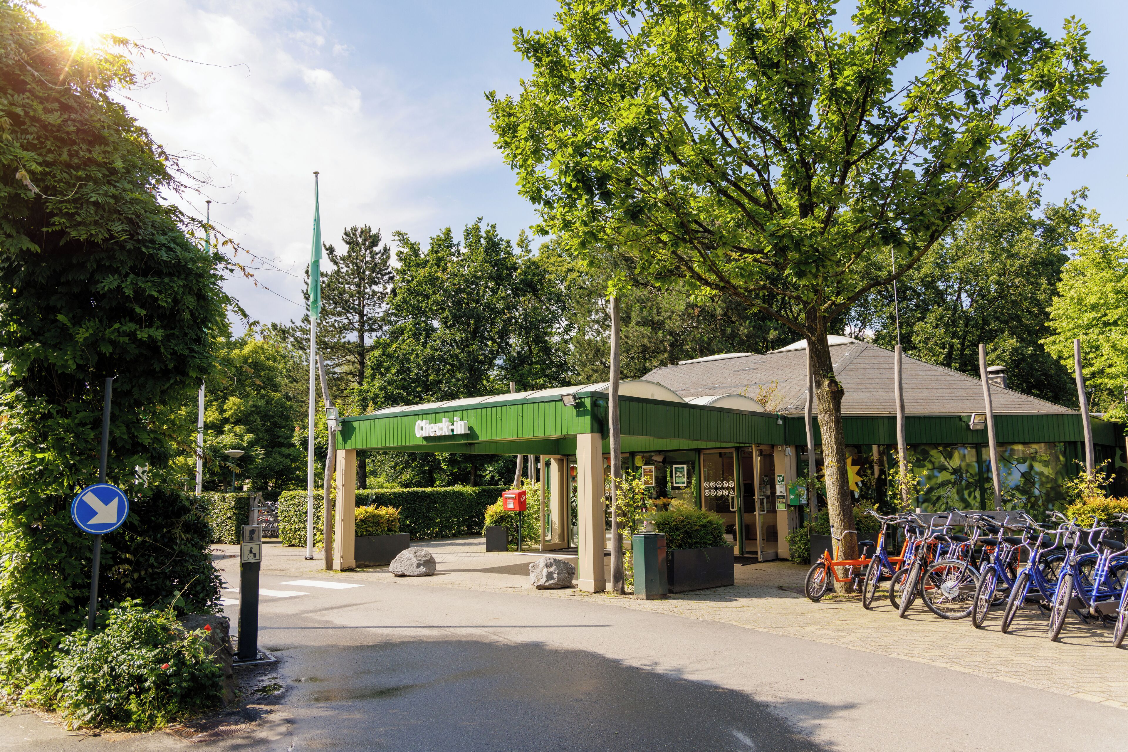 Un point d’enregistrement doté d’un auvent vert, un espace de stationnement pour vélos et un ciel dégagé.