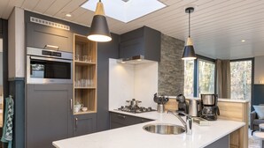 A modern kitchen with a large island, built-in appliances, and pendant lighting. - Center Parcs De Vossemeren (Lommel)