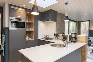 A modern kitchen with a large island, built-in appliances, and pendant lighting.