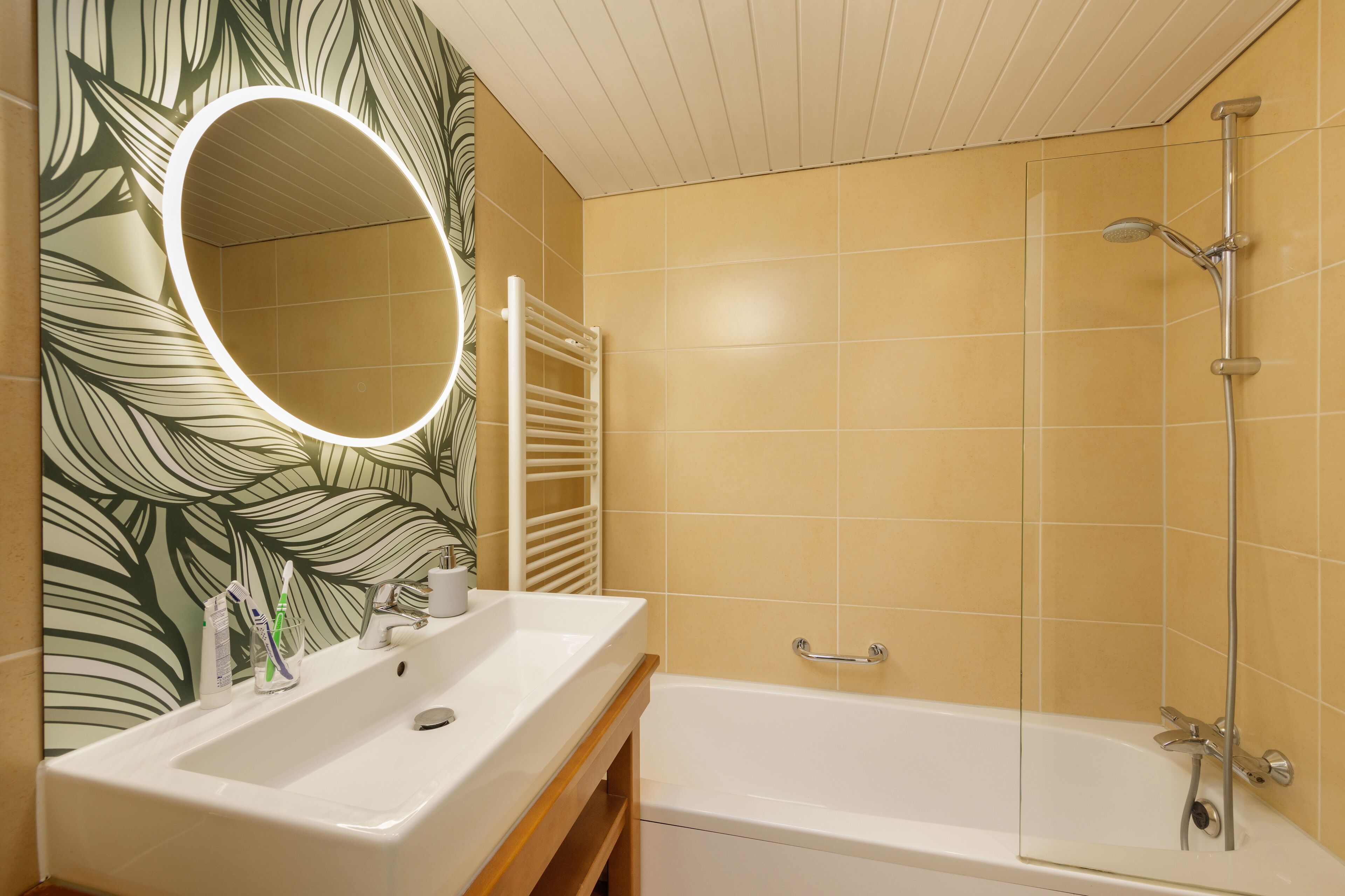 Une salle de bain avec un lavabo blanc, un miroir et une baignoire.