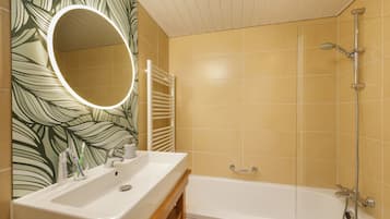 Une salle de bain avec un lavabo blanc, un miroir et une baignoire.