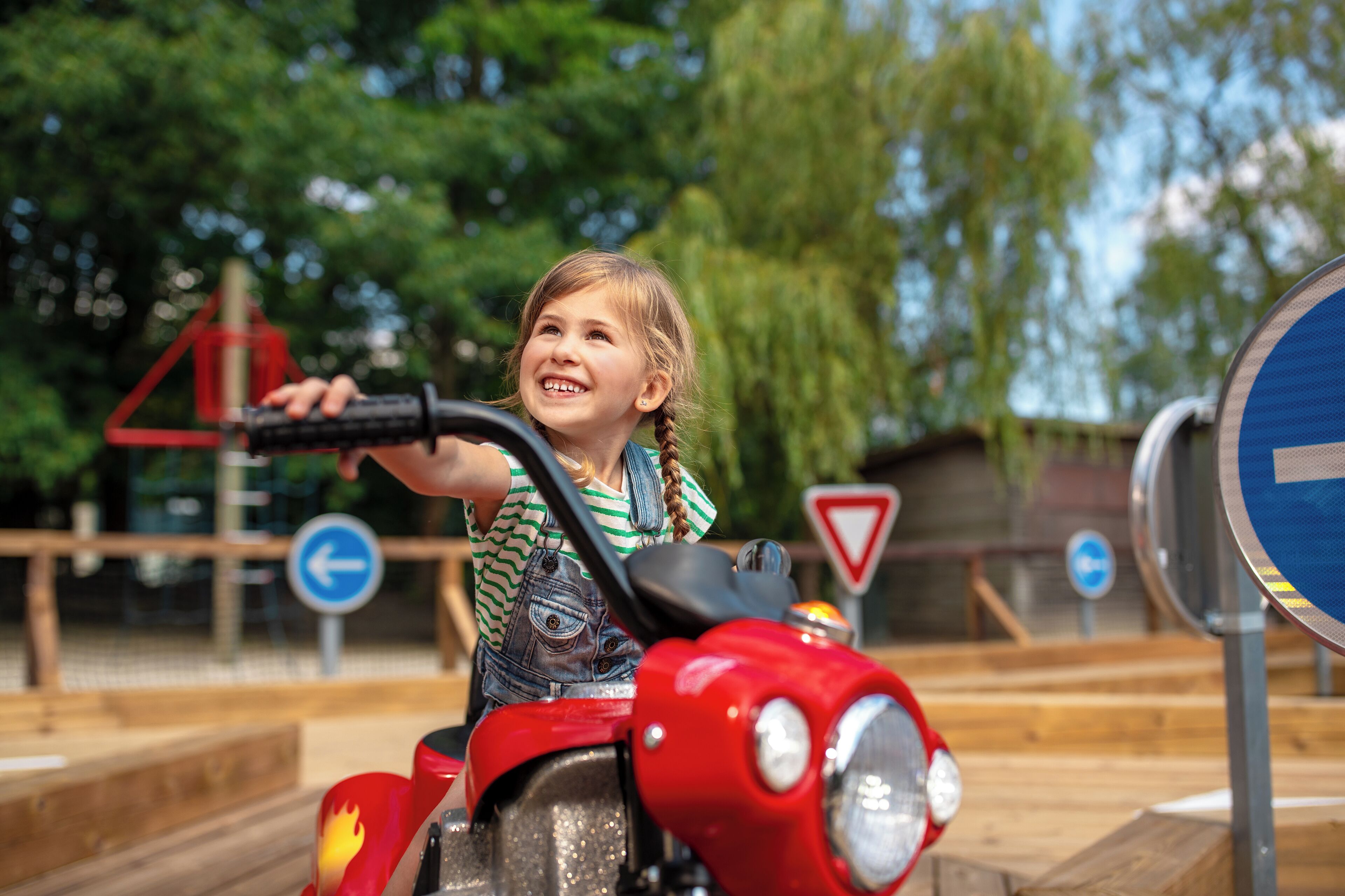 Een kind rijdt op een rode speelmotorkfiets.