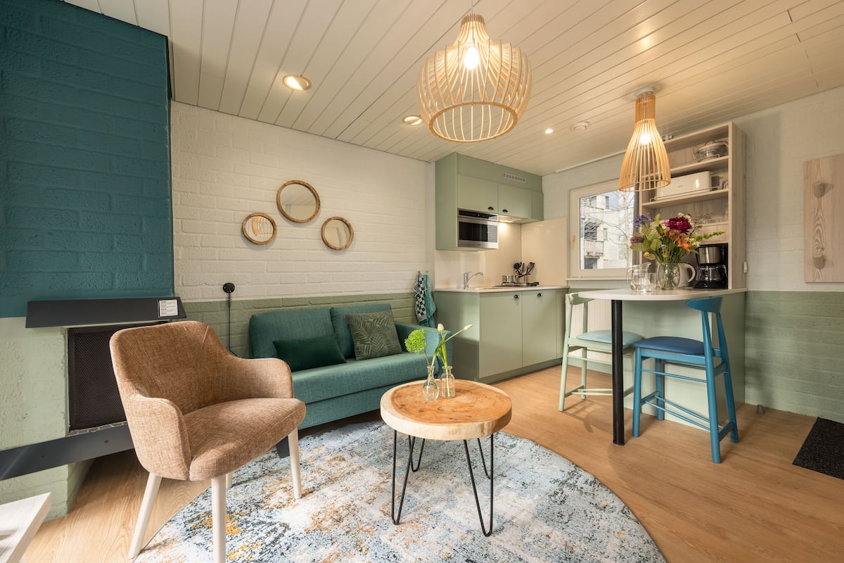 A modern living room with a sofa, a wooden coffee table, and a kitchen area with a dining table and chairs.