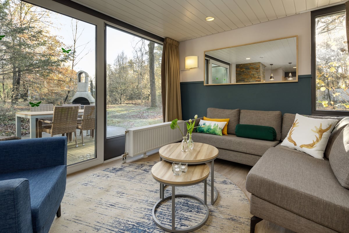 A modern living room with a sofa, a coffee table, and a dining area with chairs.