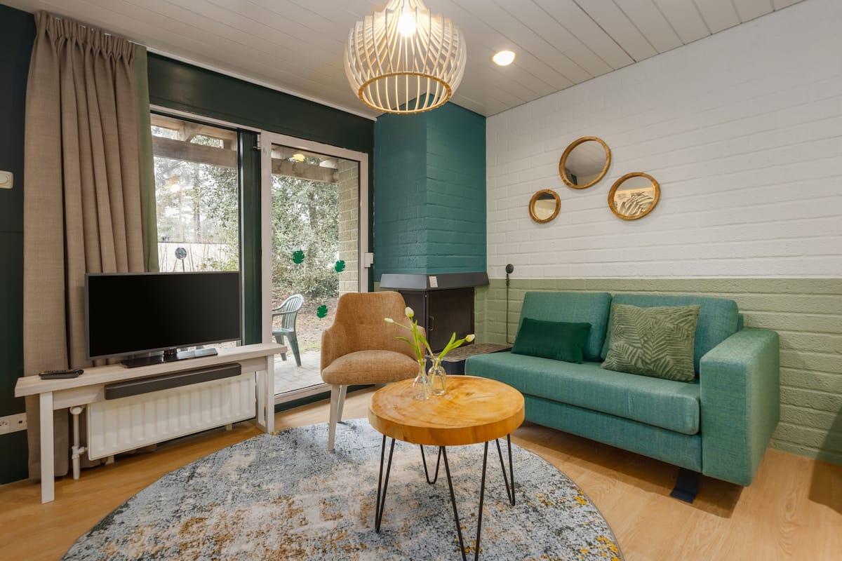 A living room with a TV, sofa, armchair, and coffee table.