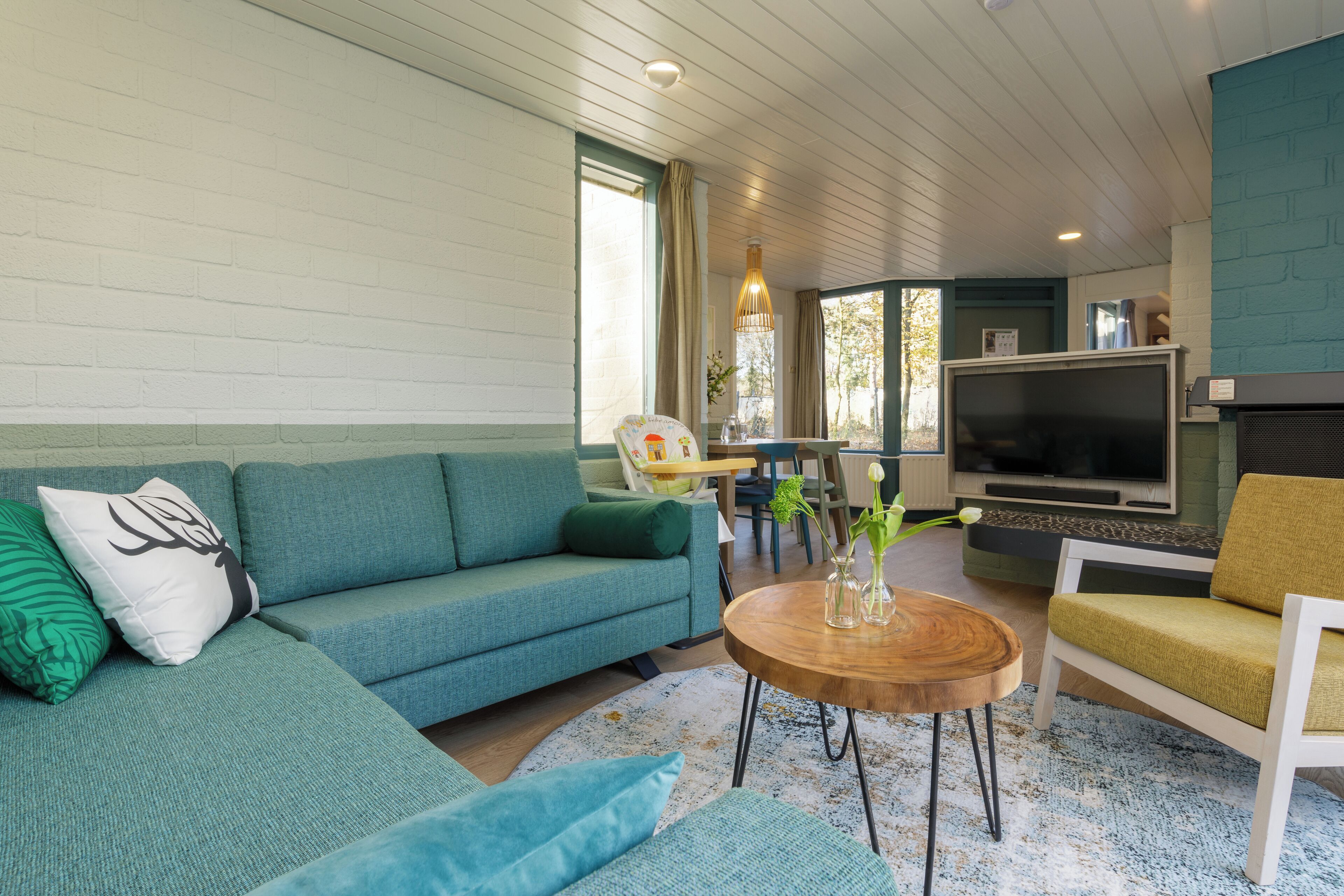 A living room with a teal sofa, a wooden coffee table, and a television.