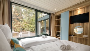 Une chambre d’hôtel avec deux lits, une télévision, un miroir et une vue sur l’extérieur.