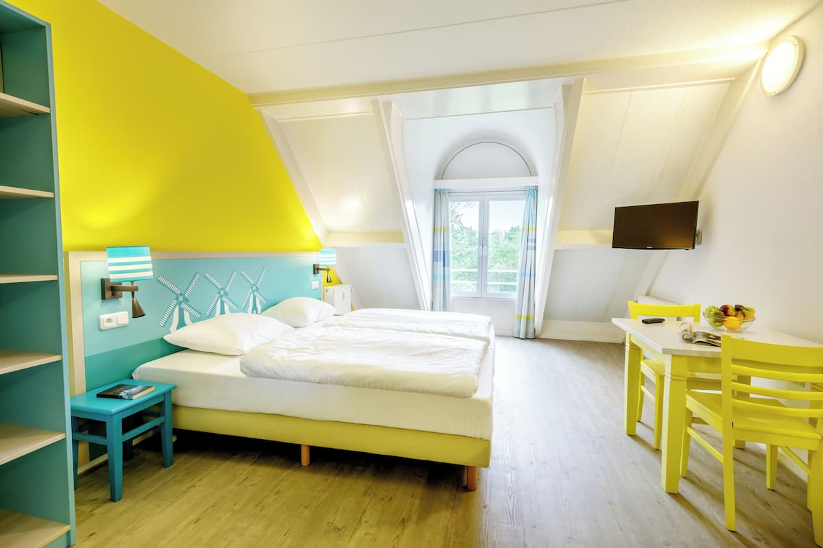 A bedroom with a bed, a desk, and a TV.