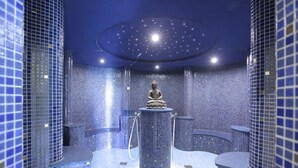 Ett modernt spa med en central Buddha-staty, kaklade väggar och ett stjärnspäckat tak.
