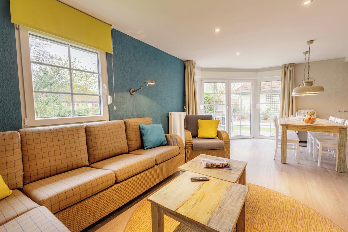 A modern living room with a sofa, armchair, and dining table.