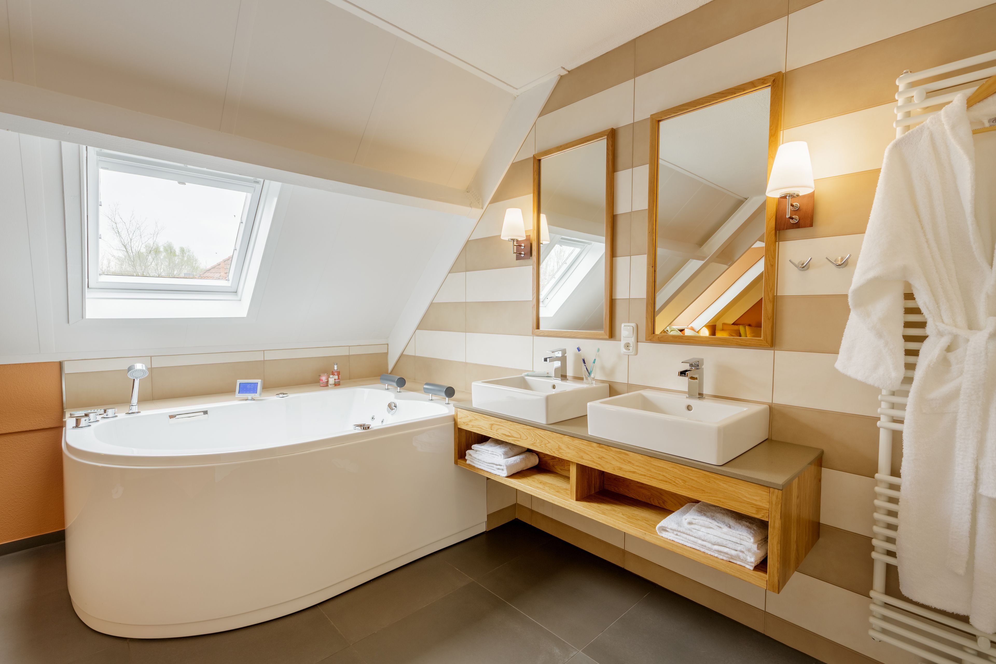 A modern bathroom with a freestanding bathtub, two sinks, and a large mirror.