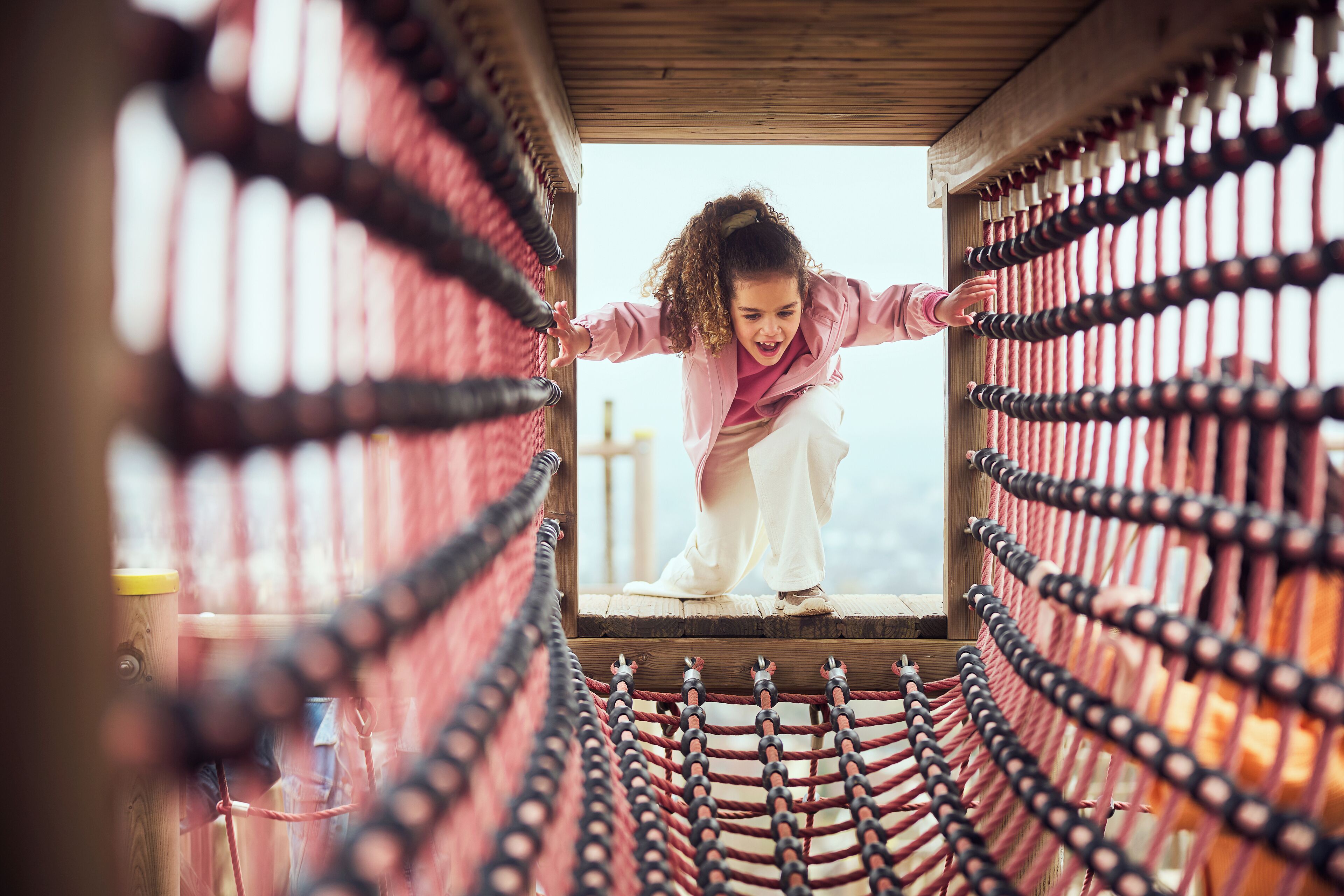 A person climbing a rope ladder structure.