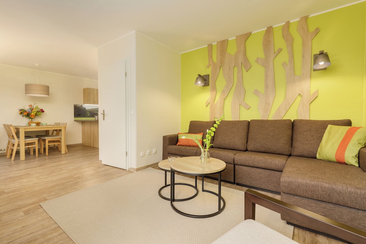 Un salon moderne comprenant un canapé, une table basse et un coin repas avec une table et des chaises.