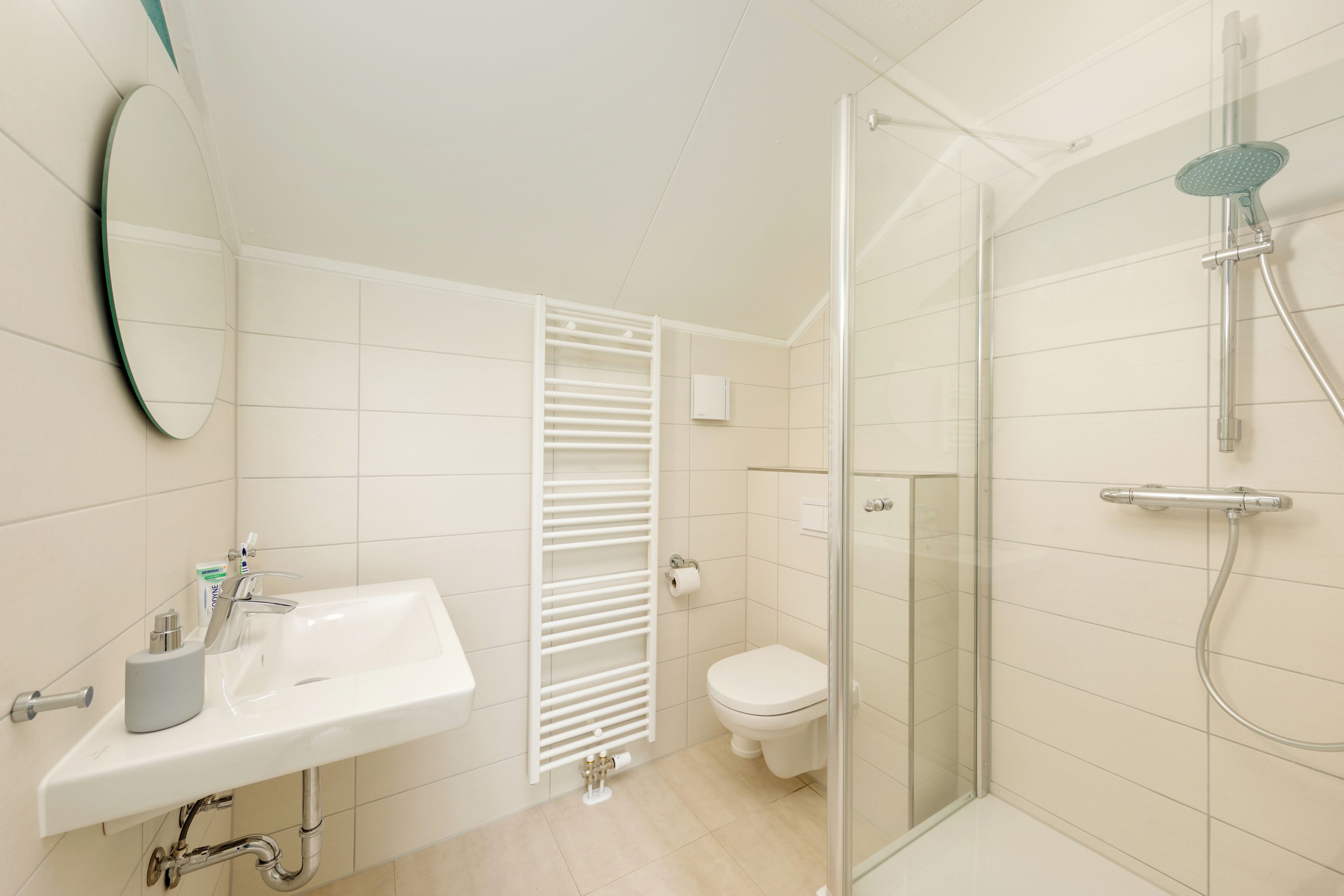 A modern bathroom with a white sink, toilet, and glass-enclosed shower.
