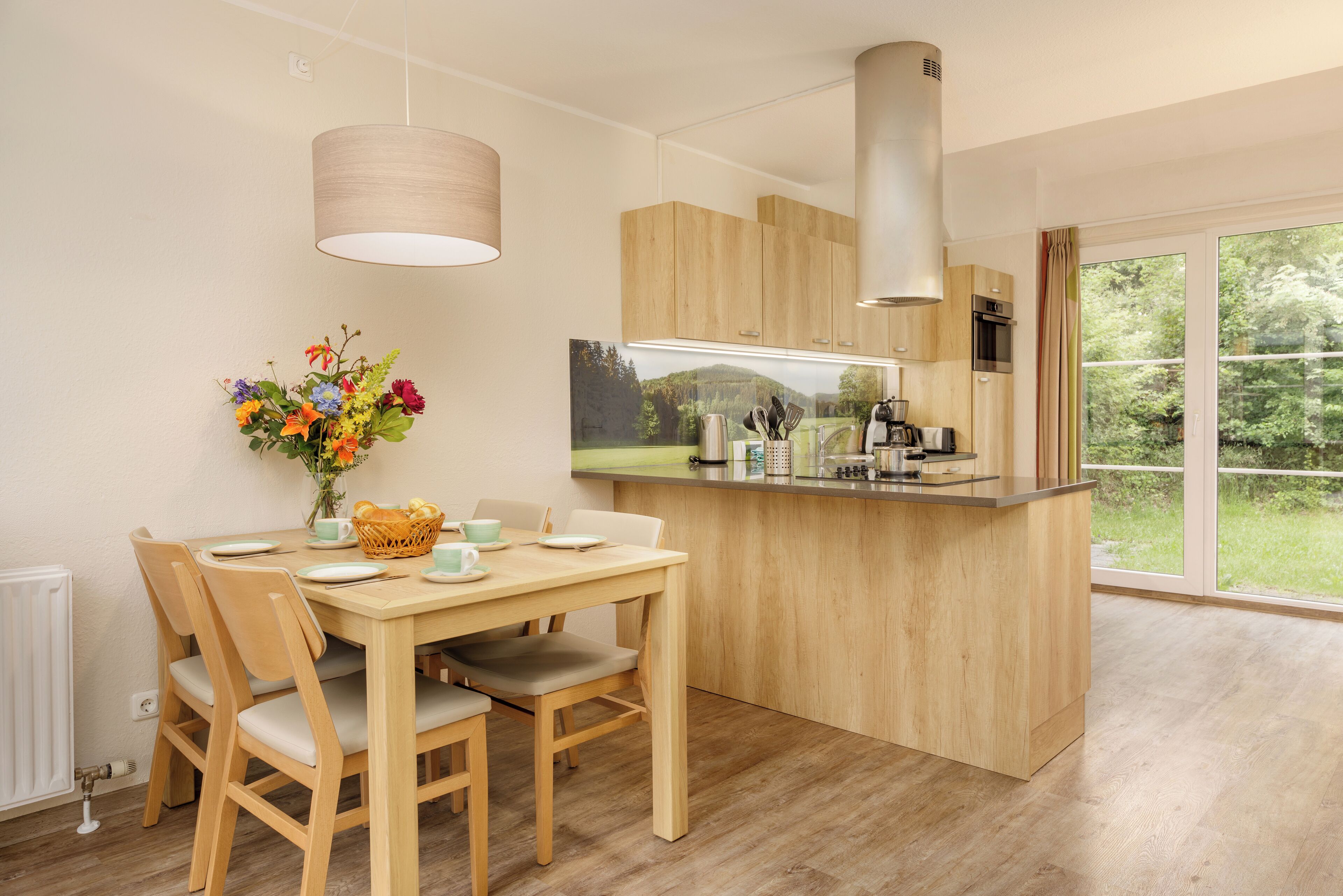 Eine moderne Küche mit Holzschränken, einer zentralen Kochinsel und einem Essbereich mit Stühlen und Tisch.
