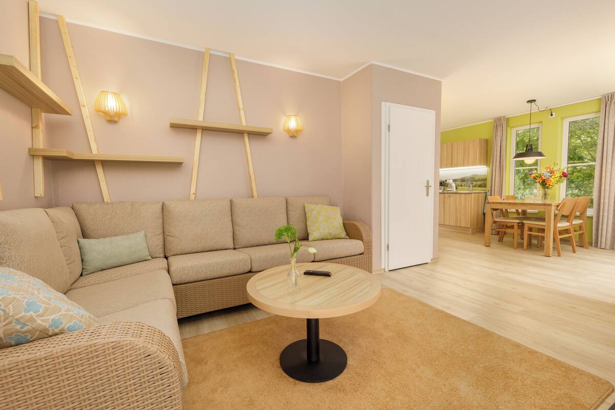 Un salon comprenant un canapé, une table basse ronde et un coin repas avec une table et des chaises.