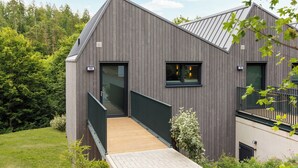 A modern building with a wooden exterior, a balcony, and a small wooden deck. - Center Parcs Park Eifel (Gunderath)