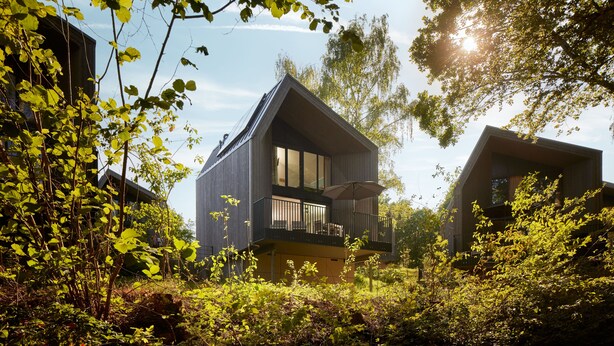 A modern house with a balcony, surrounded by lush greenery and trees. - Center Parcs Park Eifel (Gunderath)