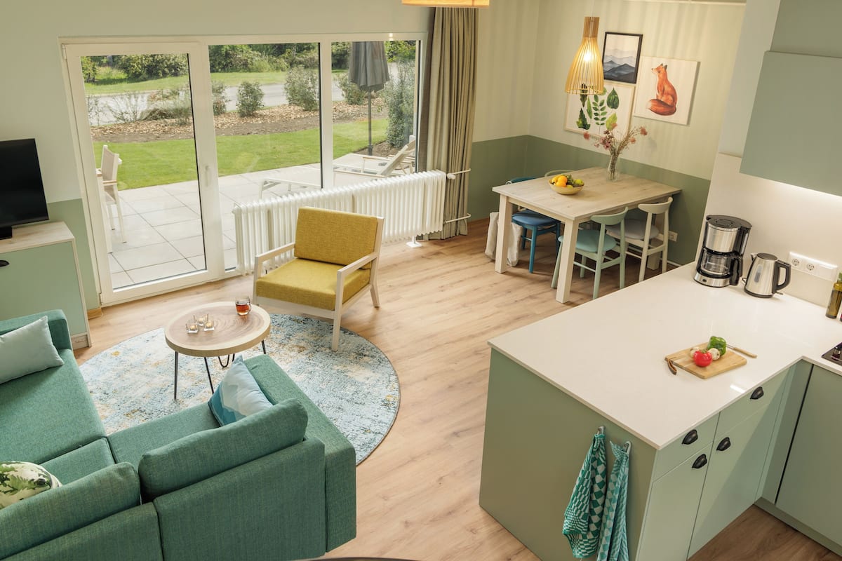 Une cuisine moderne avec un coin repas, un canapé et une vue sur le jardin grâce aux portes coulissantes.
