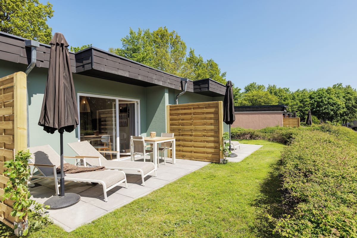 Une maison moderne dotée d’un patio, d’un espace salon extérieur et d’une clôture en bois.